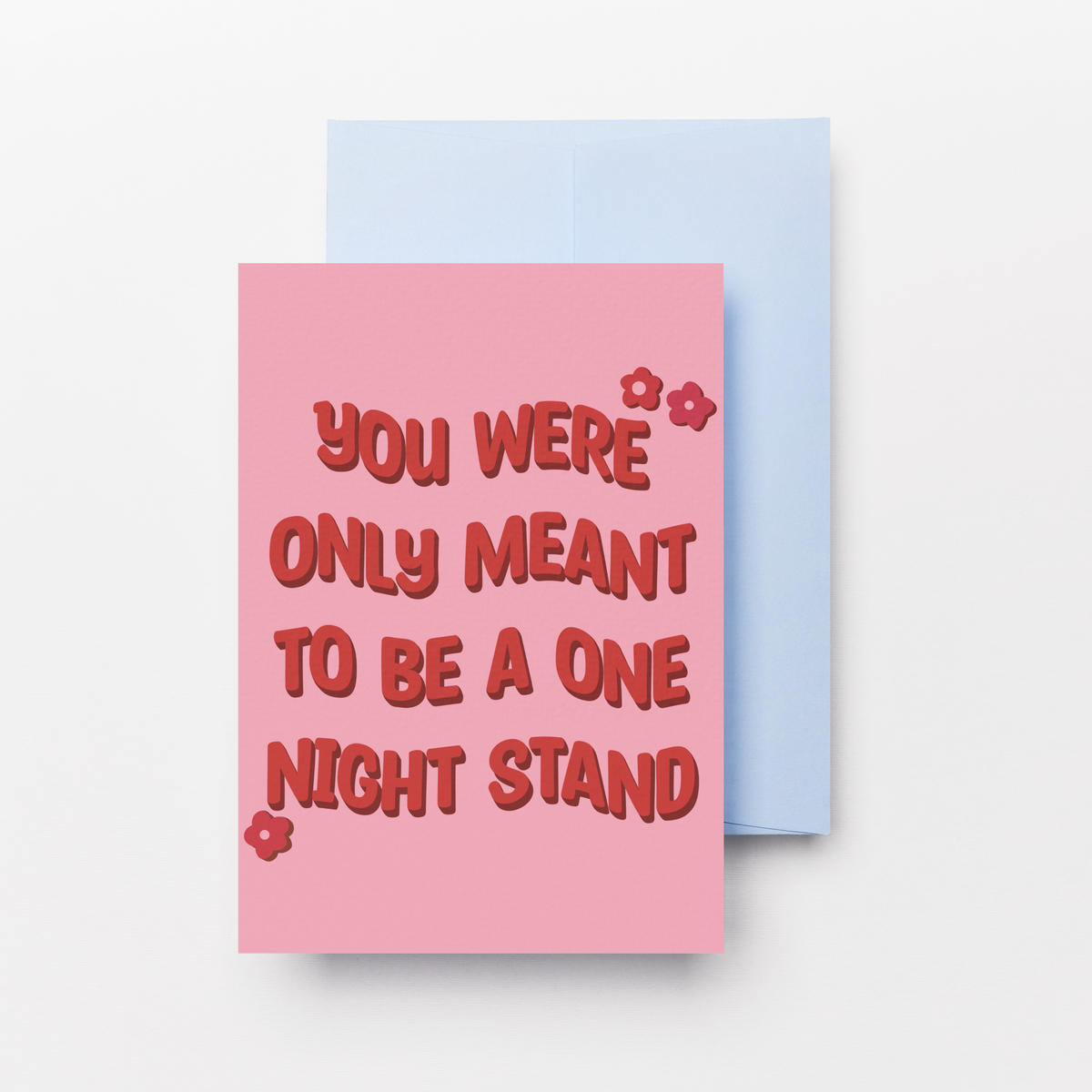 A pink greeting card with red text reading 'YOU WERE ONLY MEANT TO BE A ONE NIGHT STAND' is shown with a light blue backing card on a clean white background.