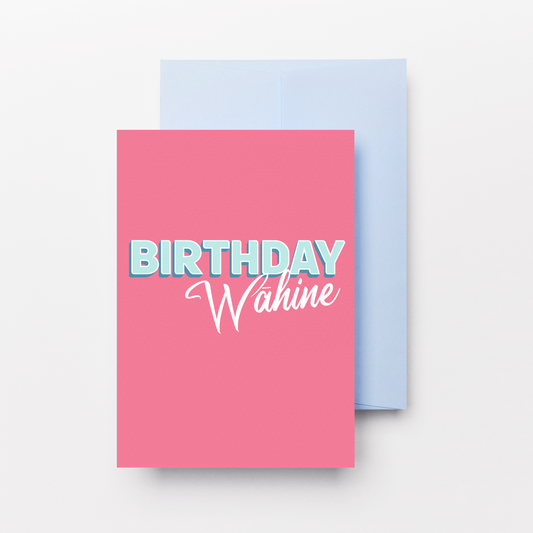 A pink birthday card with the text 'BIRTHDAY Wahine' in light blue and white, shown with a light blue envelope behind it on a clean white background.